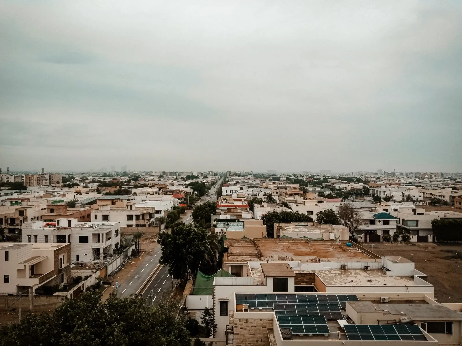 Aerial cityscape showing residential buildings and solar panels under a cloudy sky.